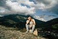 Tired traveling man resting on hill. Exhausted male tourist sitting on stone and sweetly yawning with closed eyes after