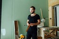 Tired unhappy man standing with corner ruler in rennovating apartment