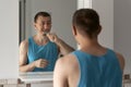 Tired unshaven man brushes his teeth in bathroom in front of mirror. Morning routine.Oral hygiene