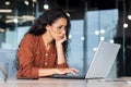 Tired and upset young Hispanic woman sitting in office with a laptop, feeling bored Royalty Free Stock Photo