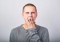 Tired wanting to sleep young man yawning and closed mouth the hand on blue background Royalty Free Stock Photo