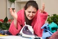 The tired wife irons clothes with an iron on the ironing board and cries. Fatigue of housewives, annoying daily routine Royalty Free Stock Photo