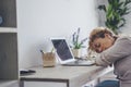 Tired woman asleep in fron tof laptop computer at home in office workstation room. Adult female people sleeping for overwork Royalty Free Stock Photo