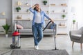 Tired woman cleaning floor with vacuum cleaner in living room Royalty Free Stock Photo