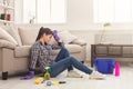 Tired woman cleaning house with lots of tools