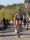 Tired woman cycling and looking down, competitors behind