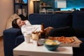 Tired woman falling asleep couch after large fast food takeaway dinner in front of television Royalty Free Stock Photo