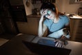 Tired woman in headphones and glasses working overtime over a laptop. Female freelancer working remotely at home in the Royalty Free Stock Photo