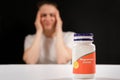 A tired woman and a jar of magnesium citrate. Dietary supplements for fatigue, irritability and insomnia