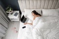 Tired woman with laptop and smartphone sleeping in bed at home, above view Royalty Free Stock Photo