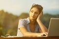 Tired woman outdoors with laptop yearns for break