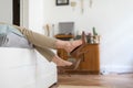 Tired woman is resting taking off her brown high-heeled shoes after work or walking, lying on the sofa. uncomfortable shoes