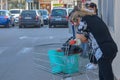 A tired woman with shopping cart. Woman in her 40-ies goes for shopping during pandemic,green bags.Dark shirt