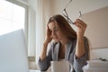 Tired woman sitting at desk with laptop, holding head, resting on hand, sleeping at workplace, bored young female Royalty Free Stock Photo