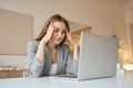 Tired woman sitting at desk with laptop, holding head, resting on hand. Royalty Free Stock Photo