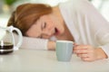 tired woman sleeping on kitchen table drinking coffee Royalty Free Stock Photo