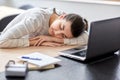 Tired woman sleeping on table with laptop at home Royalty Free Stock Photo