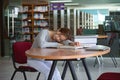 Tired woman student sleeping on desk in library Royalty Free Stock Photo