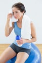 Tired woman with towel around neck and waterbottle on exercise ball Royalty Free Stock Photo