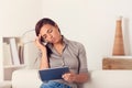 Tired woman using a digialt tablet on a couch Royalty Free Stock Photo