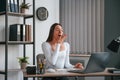 Tired woman yawns. Young female beautiful office worker in white clothes is in the office