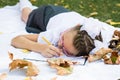 Tired of writing homework, a schoolgirl lay down to relax on a blanket in an autumn sunny park. Outdoor education. Back to school Royalty Free Stock Photo