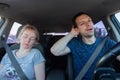 Tired yawning man driving a car and sleeping woman together during road trip. Passengers and driver wearing seat safety belts Royalty Free Stock Photo