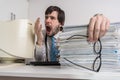 Tired yawning man in office with many documents on desk. Royalty Free Stock Photo
