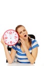 Tired yawning teenage woman holding clock