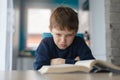 Tired 8 years old boy doing his homework at the table Royalty Free Stock Photo