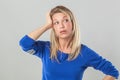 Tired young blond woman with bags touching her head