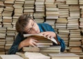 Tired young boy and books. Tired young boy sitting and sleeping with his head on the books Royalty Free Stock Photo