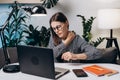 Tired young brunette woman in eyeglasses with pain neckache works at computer sitting on couch in home office at night. Neck pain Royalty Free Stock Photo