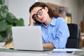 Tired young business woman touching head feeling headache migraine using laptop. Royalty Free Stock Photo