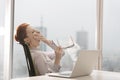 Tired young businesswoman yawning while sitting with laptop at desk in office Royalty Free Stock Photo