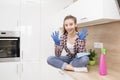 Smiling housewife after cleaning her room .A tired young cleaning lady in blue protective gloves is relaxing in the kitchen after Royalty Free Stock Photo