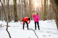 Tired young couple relaxing and hydrating after a winter workout in a snow covered forest