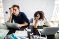 Tired young employees looking at laptops screens