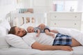 Tired young father sleeping with his baby in bed at home Royalty Free Stock Photo