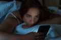 Tired young girl lies in bed and uses a smartphone, insomnia, stress and sleep disorder concept