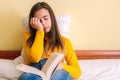 Tired young girl yawning with a book on her lap on bed Royalty Free Stock Photo