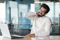 Tired young Indian man businessman working in office. Sitting at the desk, holding his neck, suffering from severe pain Royalty Free Stock Photo