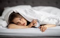 Tired young lady lying in bed with alarm clock, not wanting to get up in morning, panorama Royalty Free Stock Photo