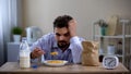 Tired young lonely man eating unhealthy sugary corn flakes for breakfast