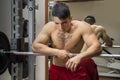 Tired young male bodybuilder resting between workouts in gym