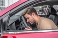 Tired young male resting his head on steering wheel