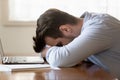 Tired young man fall asleep on table working on laptop