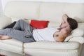 Tired young man lying on white sofa Royalty Free Stock Photo