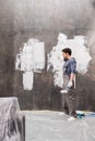 Tired young man with paint roller renovating home