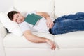 Tired young man sleeping on couch with book on lap Royalty Free Stock Photo